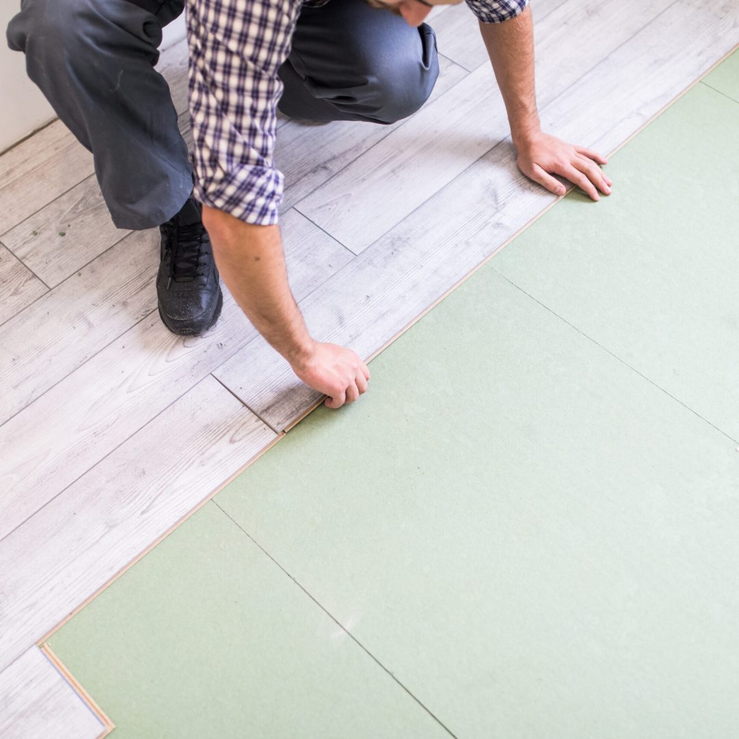 Young worker laying a floor with bright laminated flooring boards